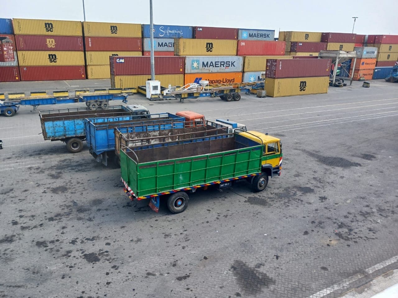Container yard with trucks and stacked shipping containers