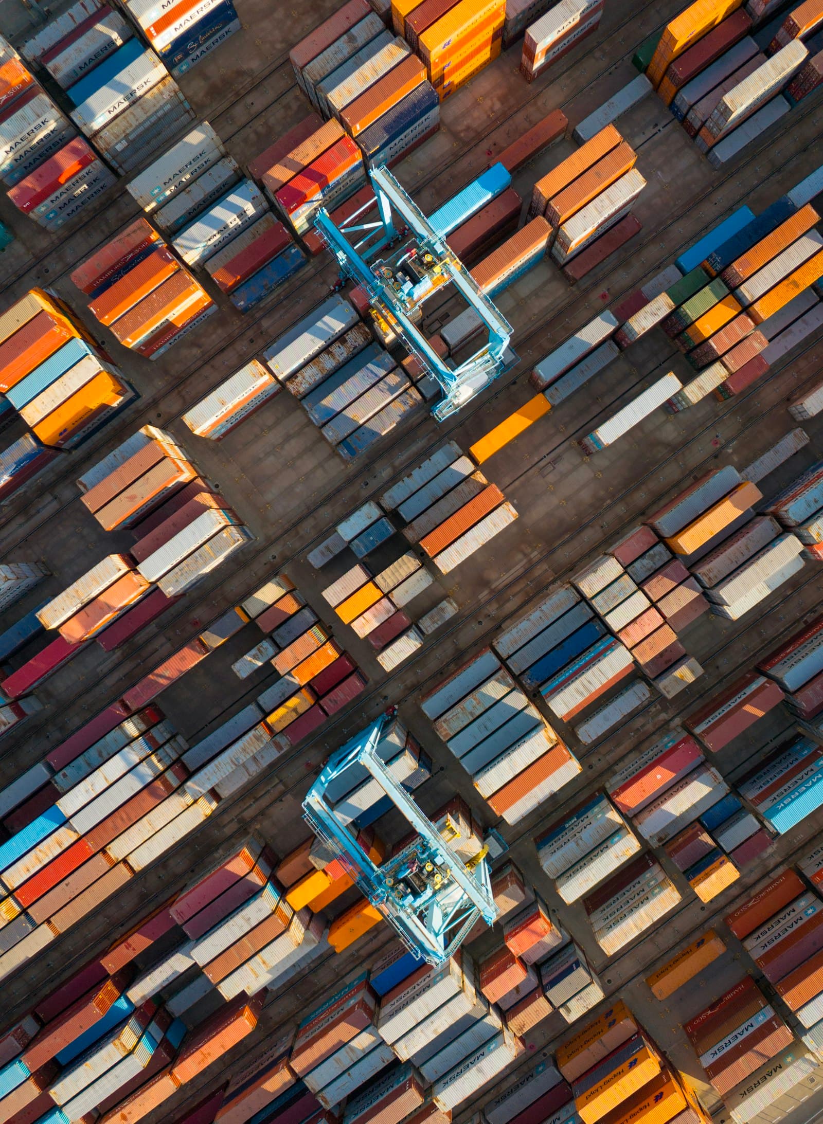 Overhead view of gantry cranes moving containers in a terminal yard