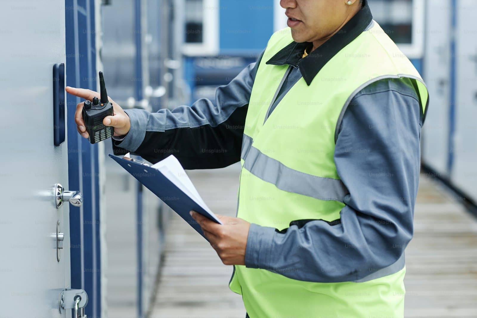 Port worker with clipboard and radio checking a container